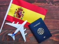 پرچم اسپانیا در کنار پاسپورت و ماکت هواپیما؛ نمادی از سفر و دریافت ویزای توریستی اسپانیا