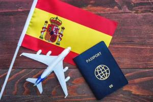 پرچم اسپانیا در کنار پاسپورت و ماکت هواپیما؛ نمادی از سفر و دریافت ویزای توریستی اسپانیا